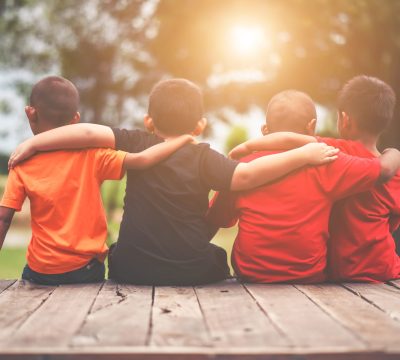 Group of kids friends arm around sitting together